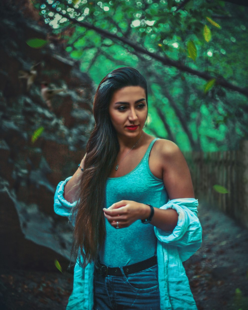 a woman with long hair standing in the woods