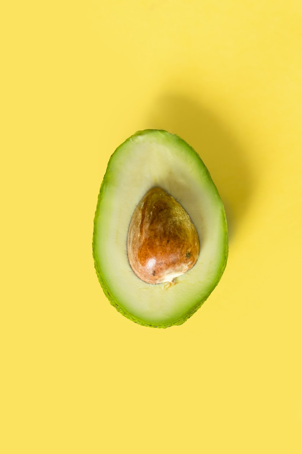 an avocado cut in half on a yellow background