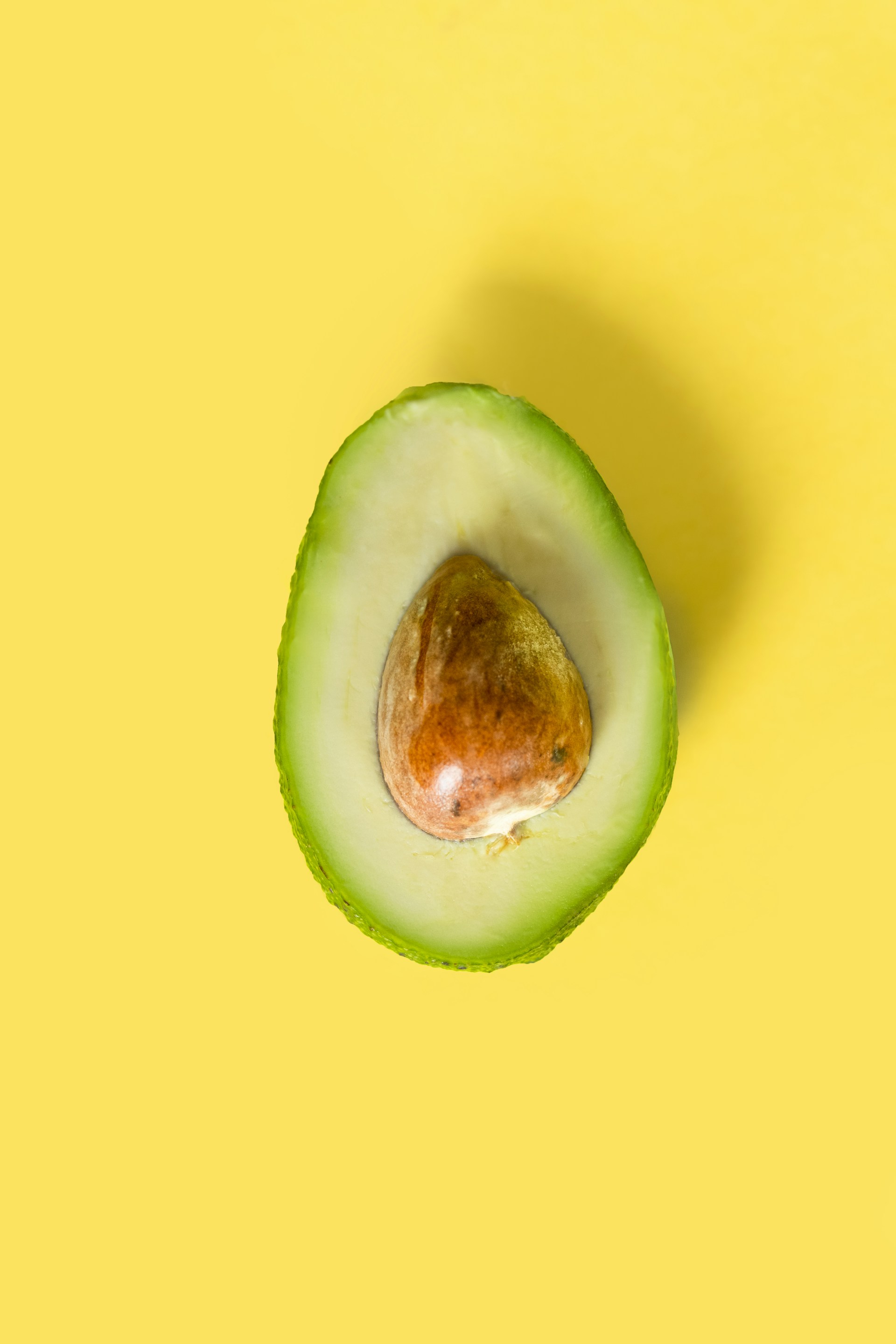 an avocado cut in half on a yellow background