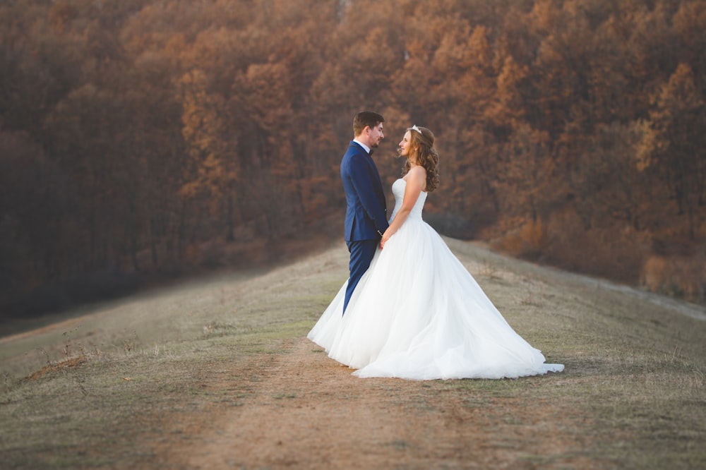 a bride and groom standing in a field