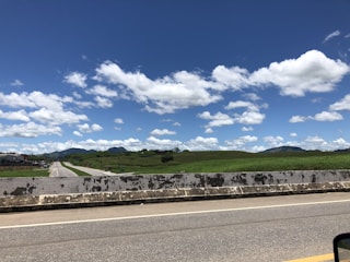 A freshly paved highway stretching through a green countryside under a clear blue sky.