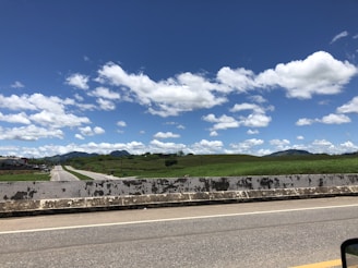A freshly paved highway stretching through rolling hills under a clear blue sky.