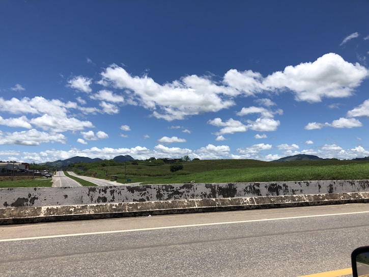 A freshly paved highway stretching through rolling hills under a clear blue sky.
