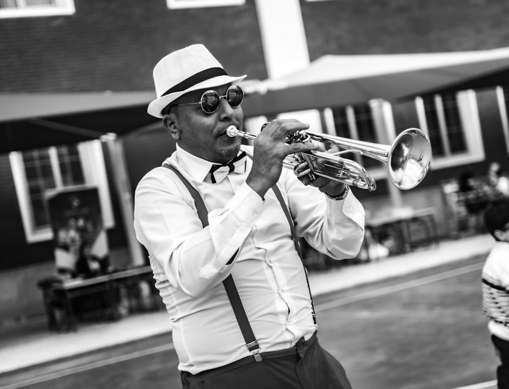 a man in a hat and sunglasses playing a trumpet