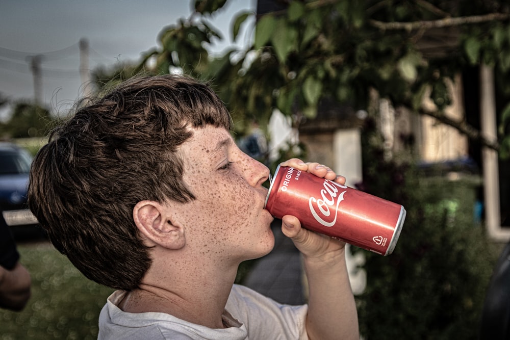 a young man drinking a coca cola from a can