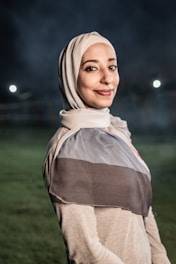 a woman in a hijab standing in a field at night