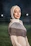 Smiling pilgrim woman wearing hijab in front of Ka'bah during sunset.