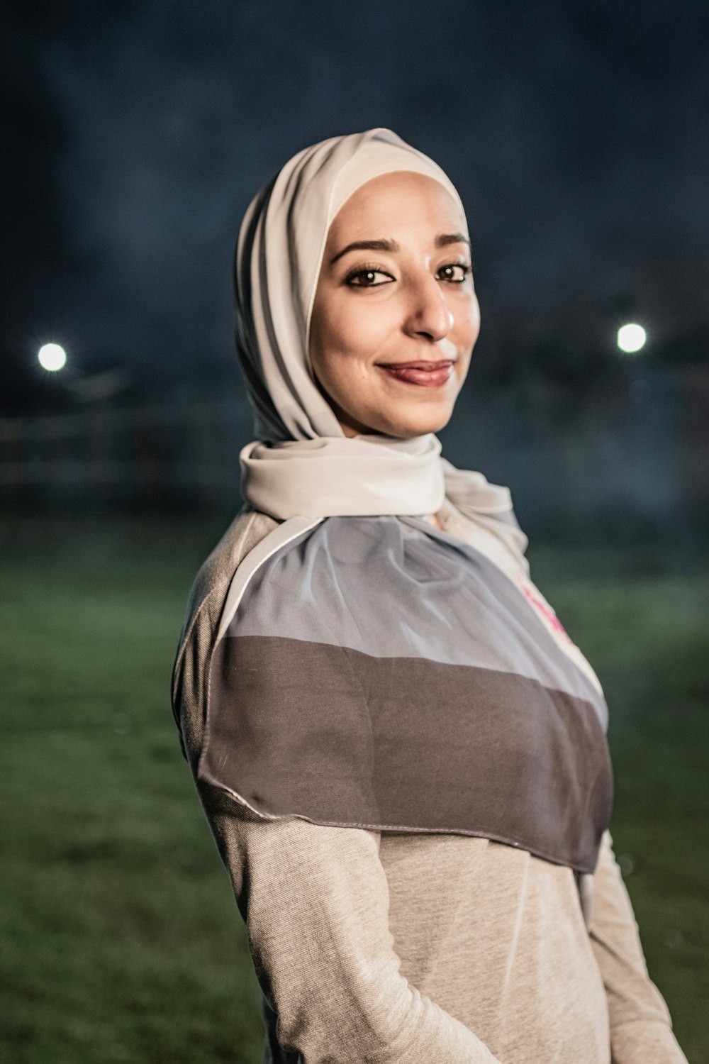 a woman in a hijab standing in a field at night