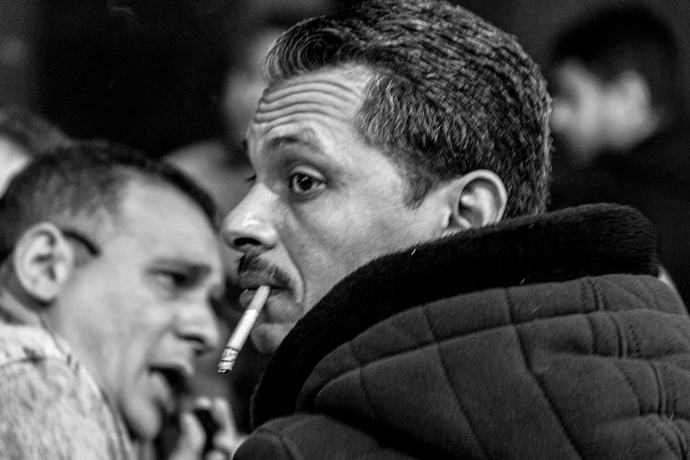 a black and white photo of a man smoking a cigarette