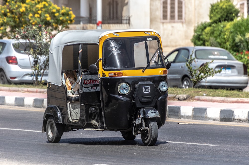 a yellow and black three wheeled vehicle driving down a street