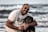 a man sitting on the beach with a dog