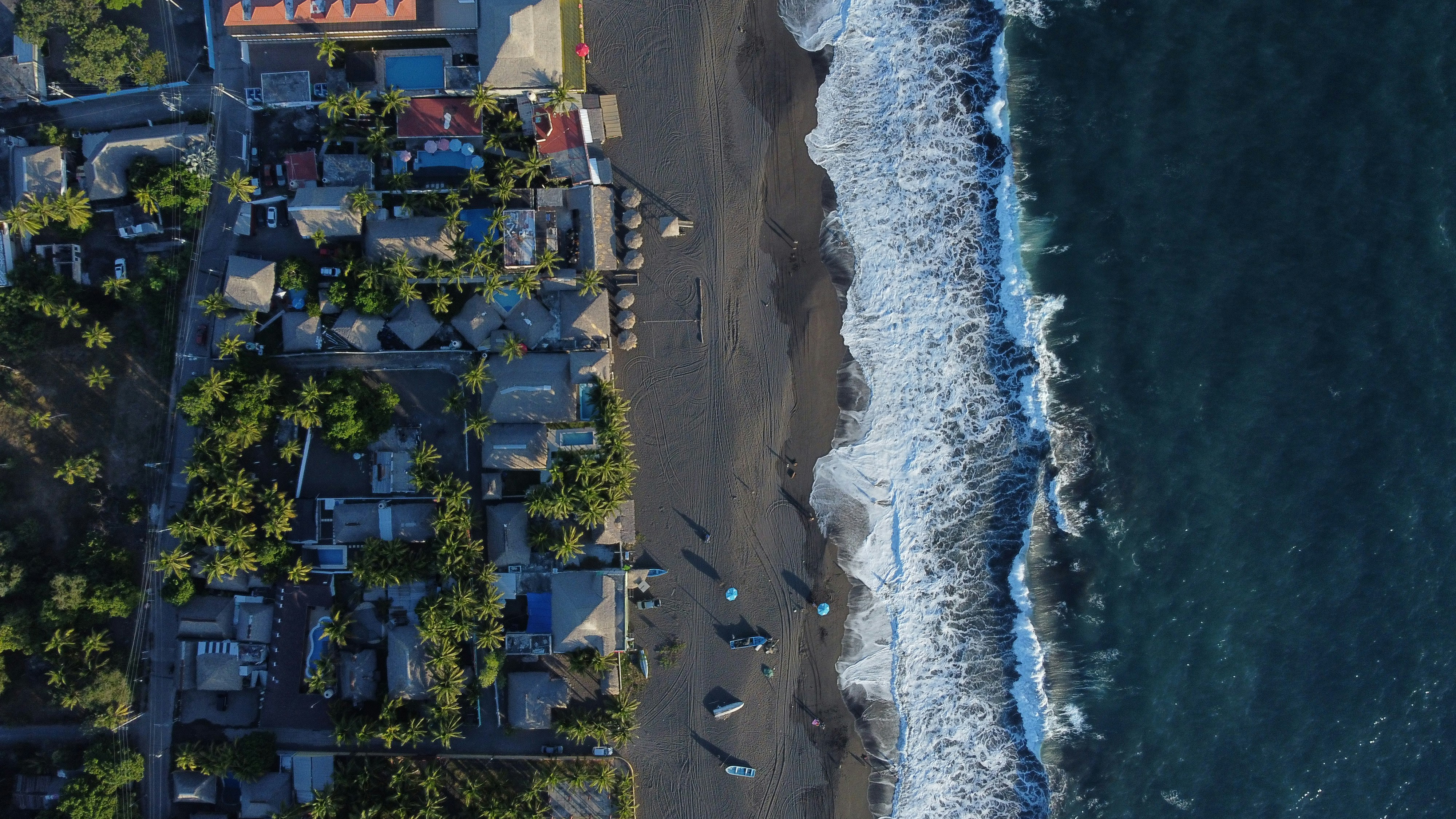 an aerial view of a beach with houses next to the ocean, 