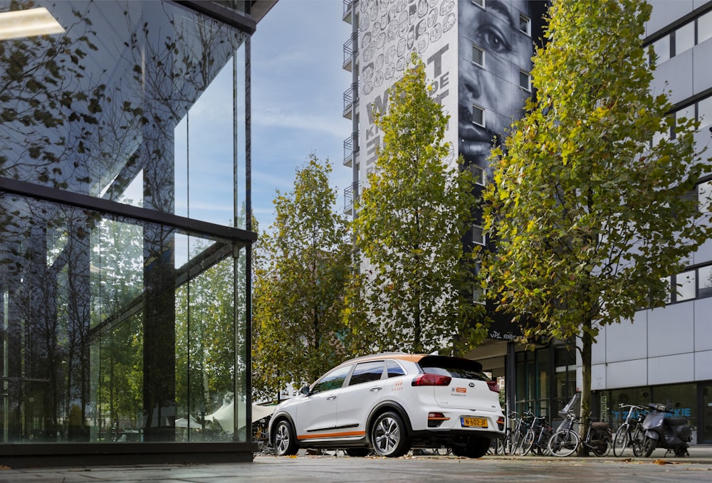 a white car parked in front of a tall building