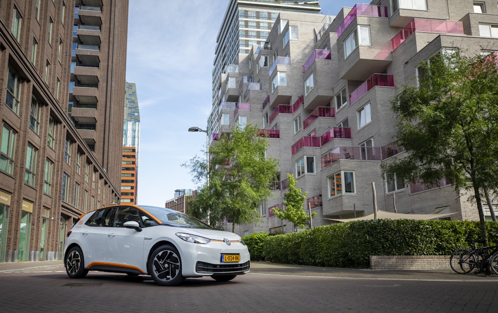 a white car parked in front of a tall building