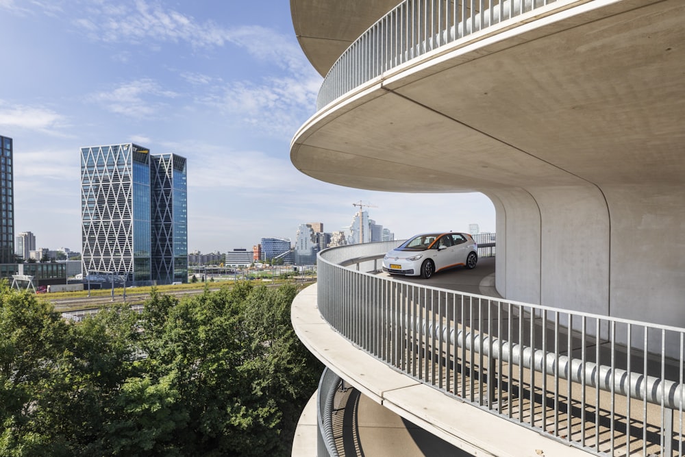 a white car driving down a road next to tall buildings