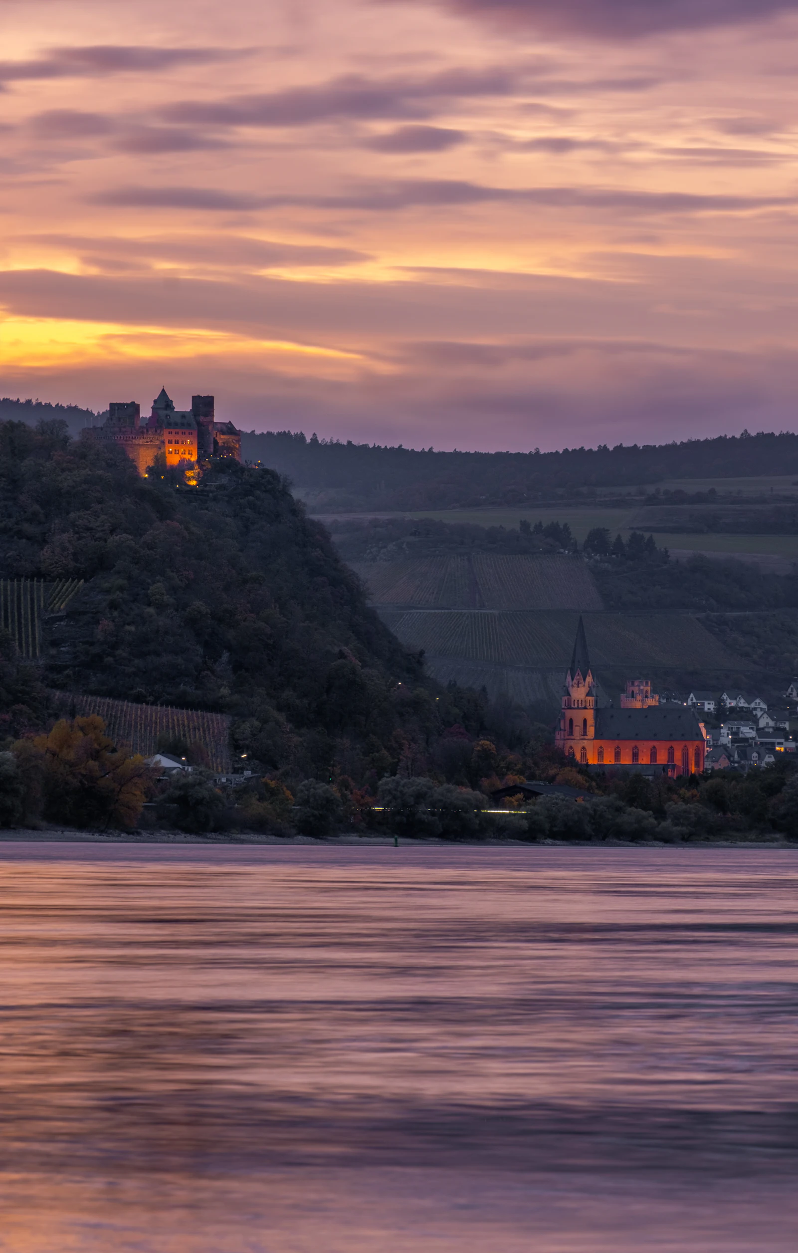 A hilltop castle and a red church glowing at dusk above the Rhine, a valley where mobile signal can dip between villages