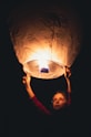 a woman holding a lit up lantern in the dark