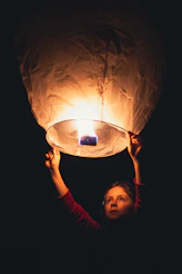 a woman holding a lit up lantern in the dark