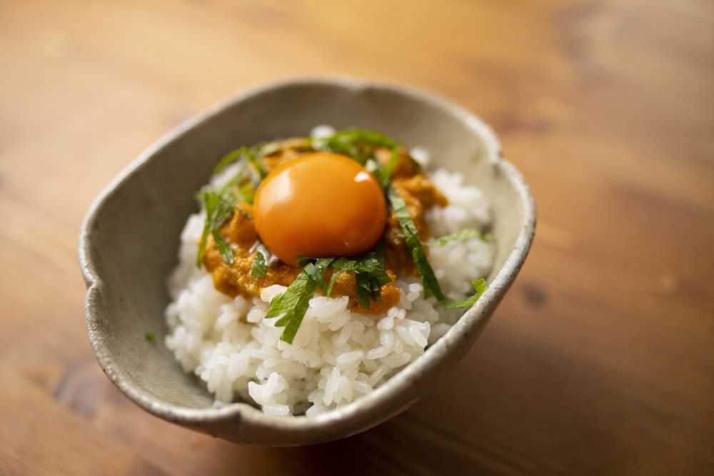a bowl filled with rice and an egg on top of it