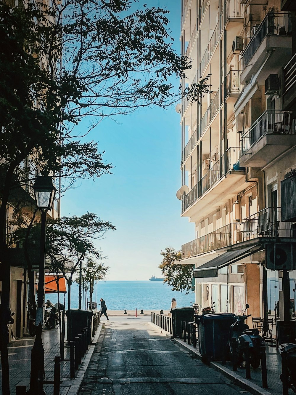 a person walking down a street next to a body of water