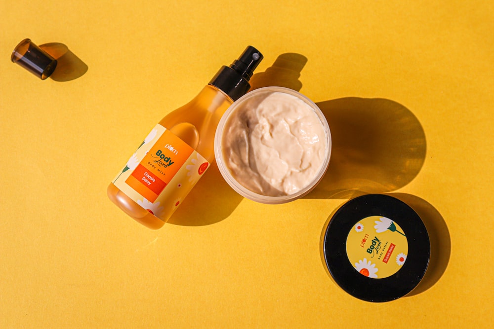 a bottle of sunscreen and a jar of sunscreen on a yellow surface