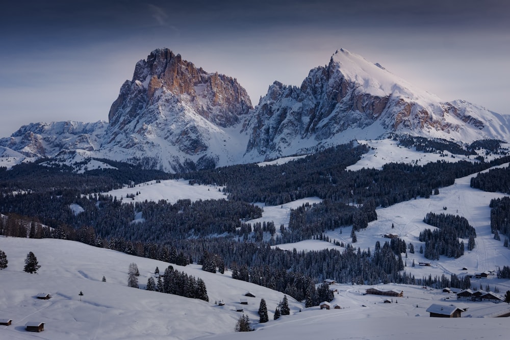 a snow covered mountain range with trees and houses