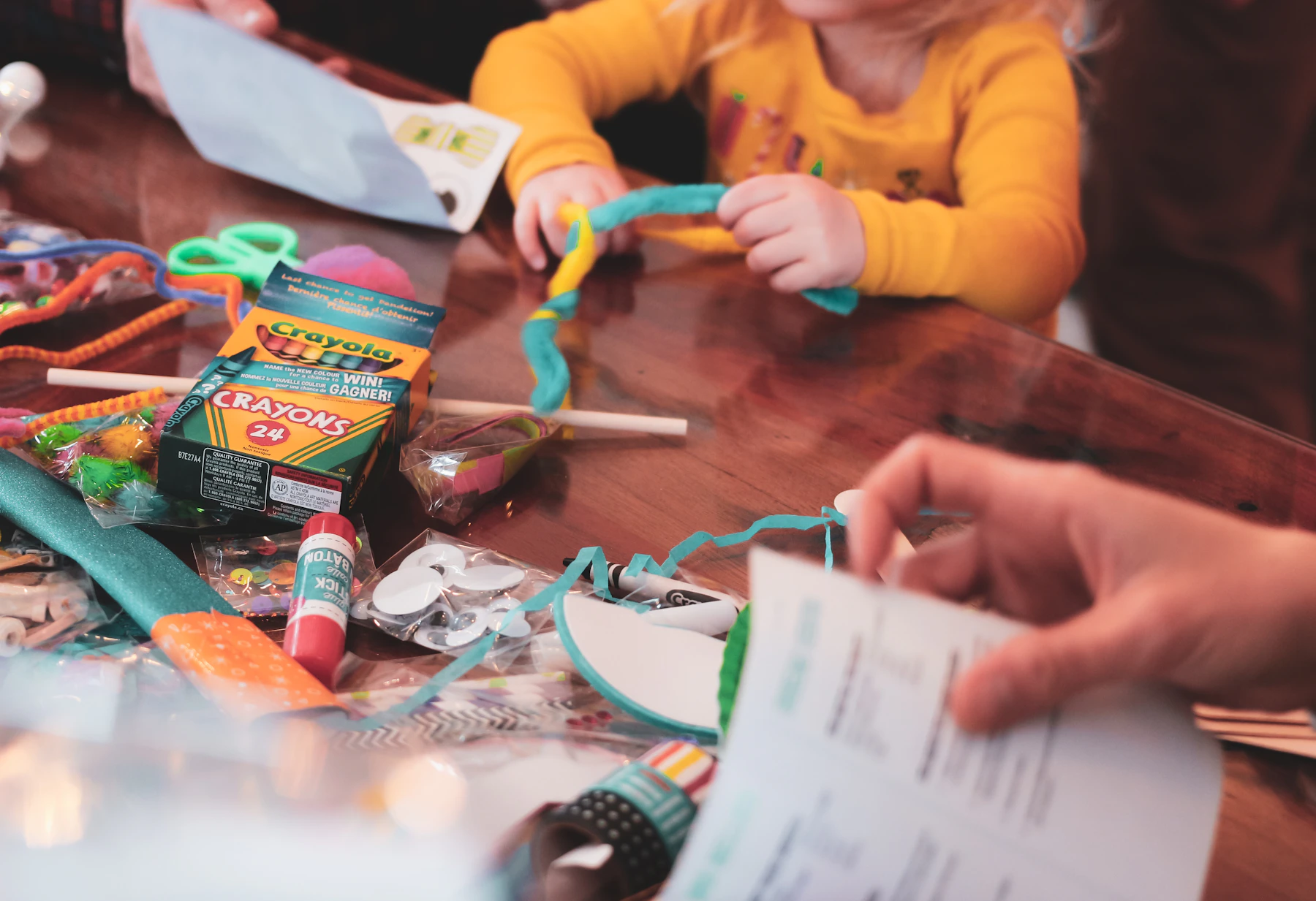 Child creating a colorful craft project with art supplies at a table