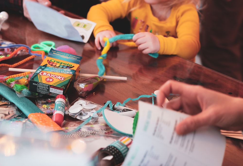 a young girl sitting at a table with lots of craft supplies
