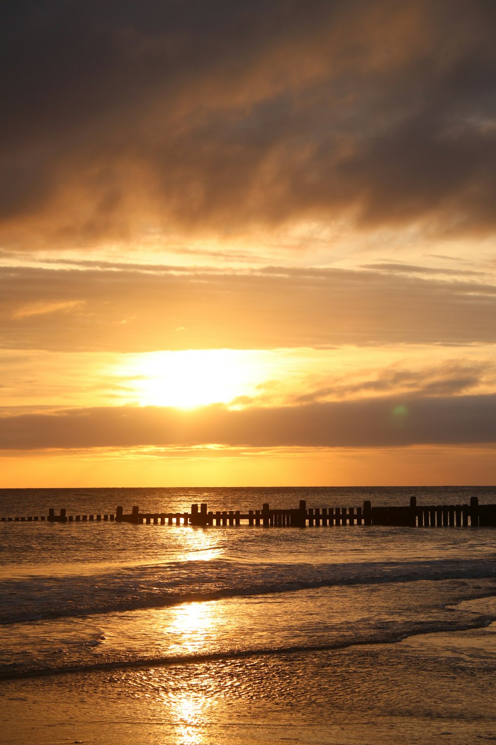 the sun is setting over the water at the beach