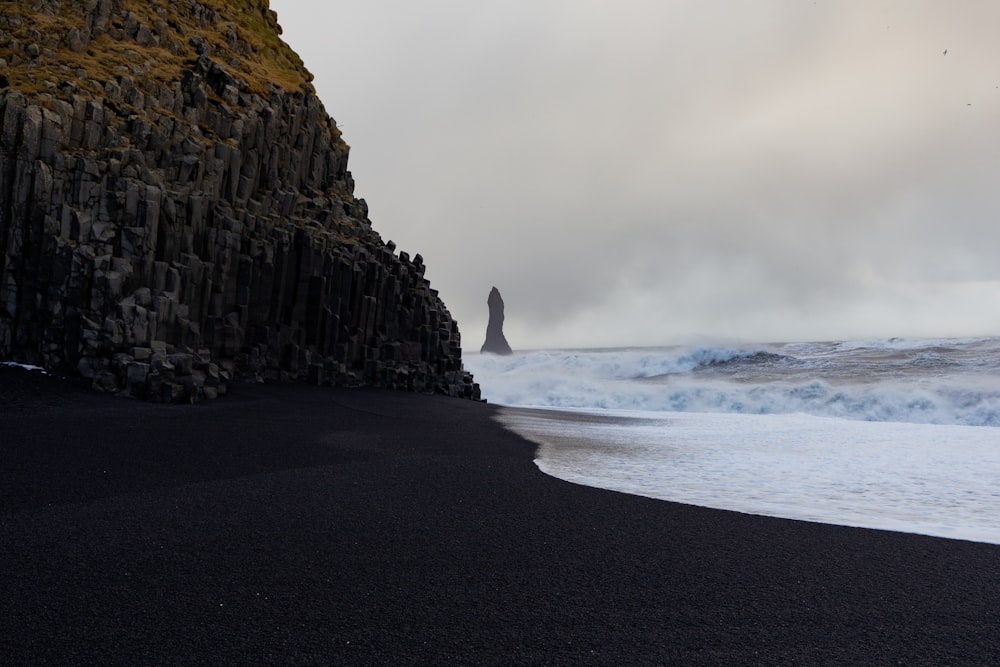 a black sand beach with waves crashing against the rocks