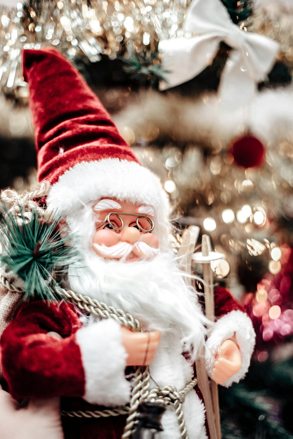 a close up of a santa clause figurine near a christmas tree