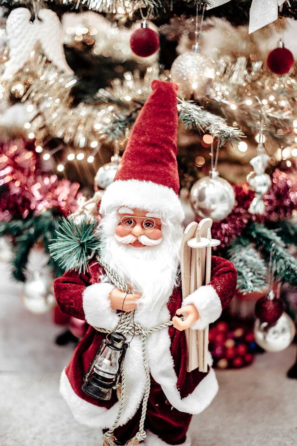 a santa clause figurine standing in front of a christmas tree