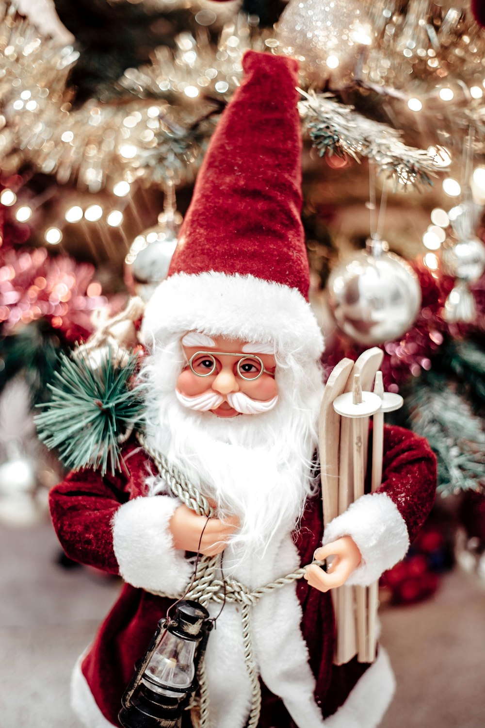 a close up of a santa clause figurine near a christmas tree