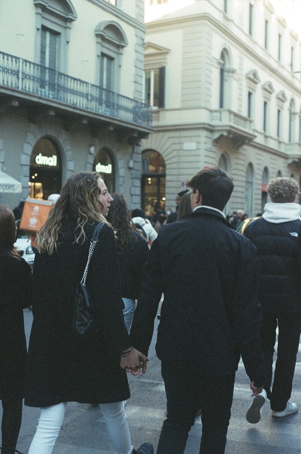 a man and a woman walking down a street holding hands