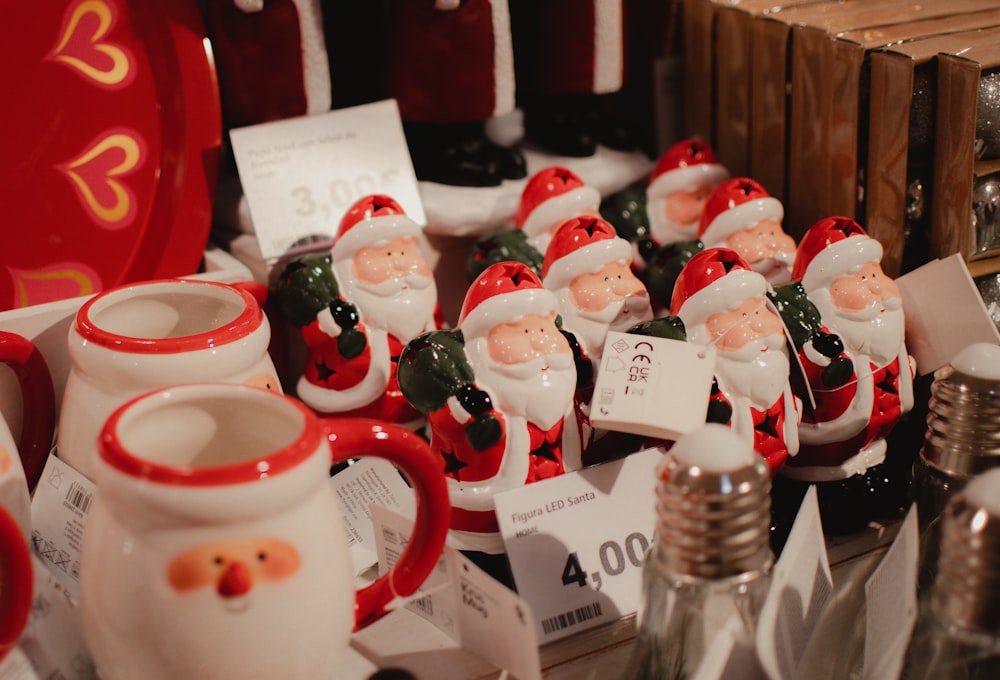 a table topped with lots of santa clause mugs