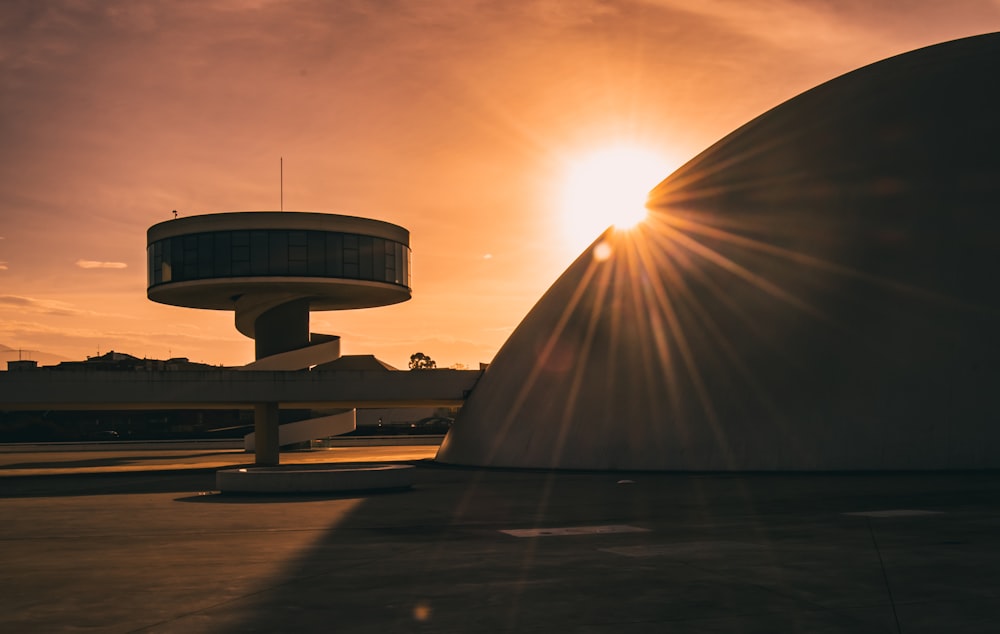 the sun is setting behind a large building