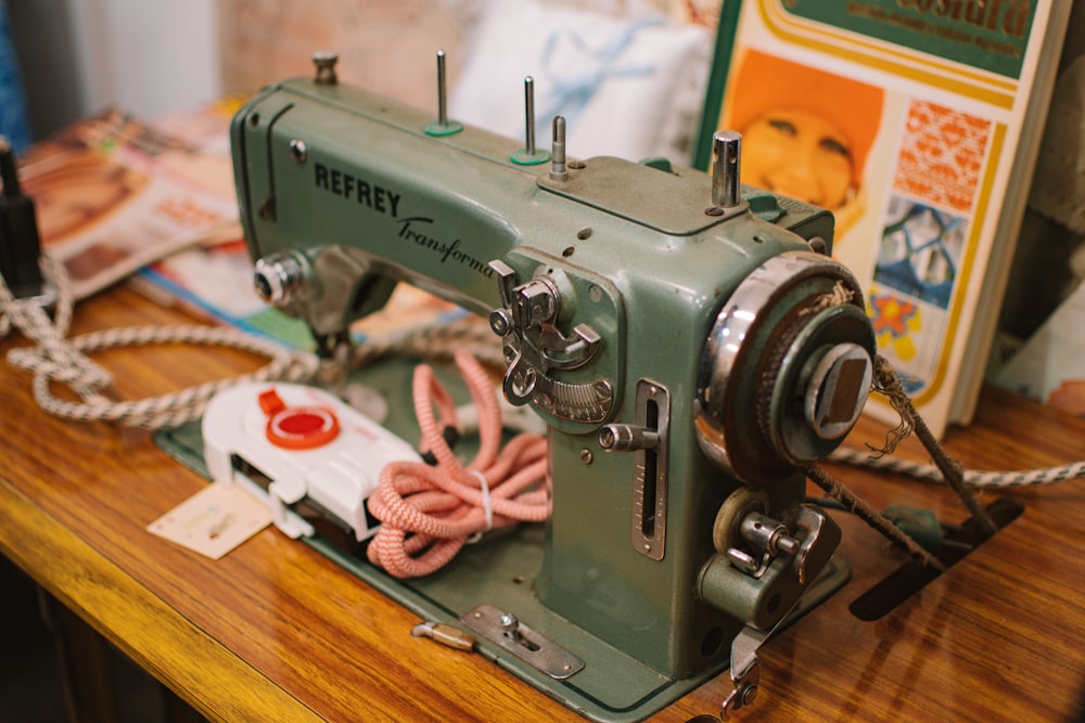 a green sewing machine sitting on top of a wooden table