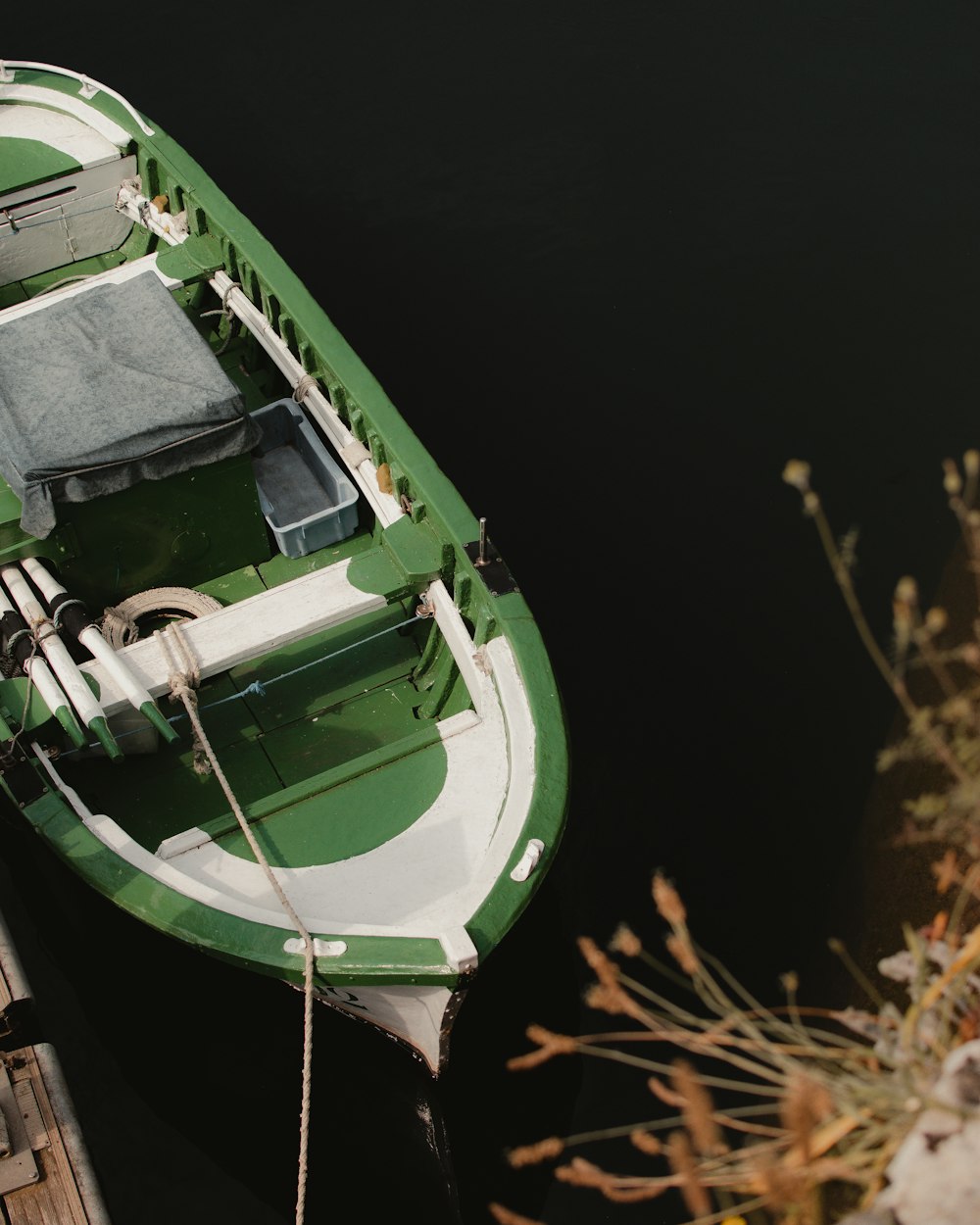 a green and white boat tied to a dock