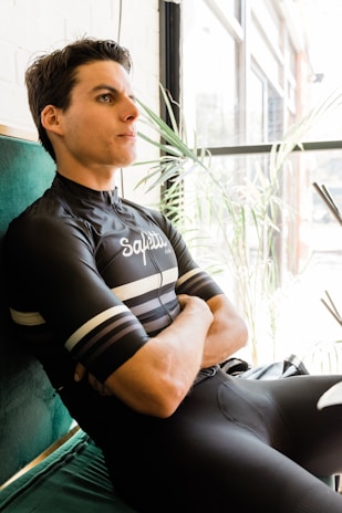 A woman cyclist smiling as she tests a saddle in her living room, surrounded by bike gear.