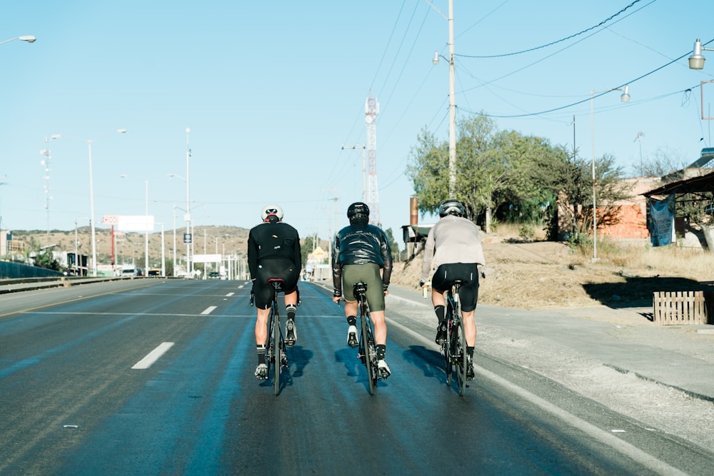three bicyclists are riding down the street together