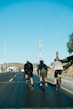 three bicyclists riding down the road on a sunny day