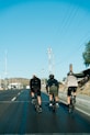 three bicyclists riding down the road on a sunny day