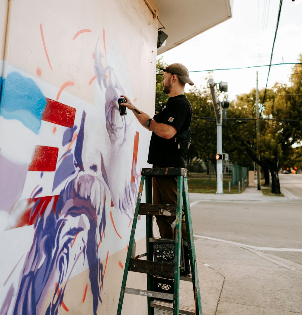 Ein Mann malt ein Wandgemälde an der Seite eines Gebäudes
