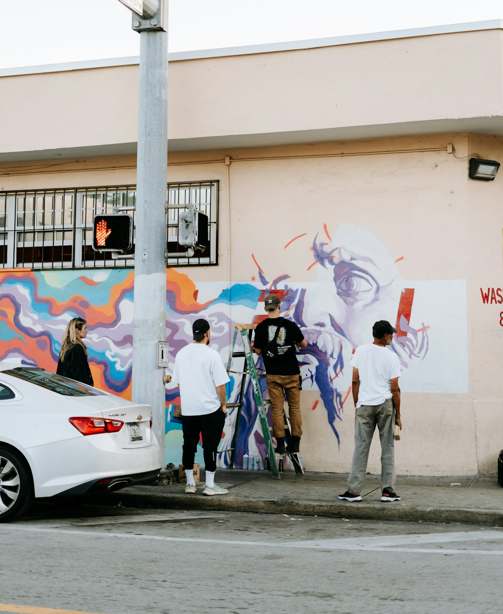 un groupe de personnes peignant une murale sur le côté d’un bâtiment