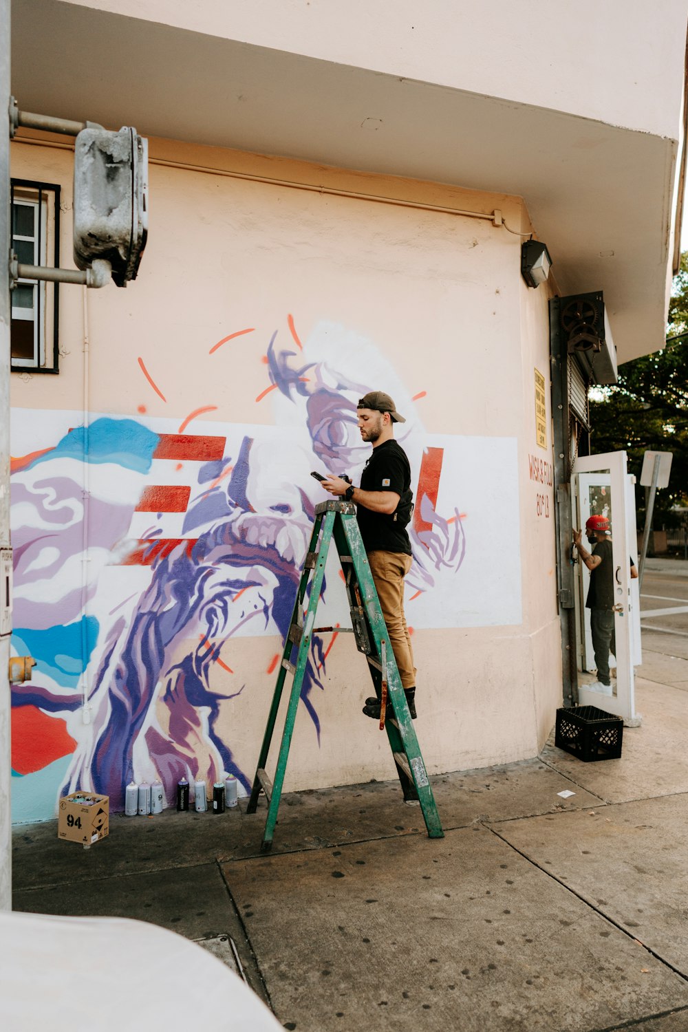 Un homme peint une peinture murale sur le côté d’un bâtiment