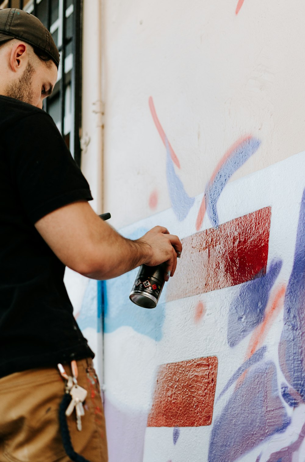 a man spray painting a wall with graffiti