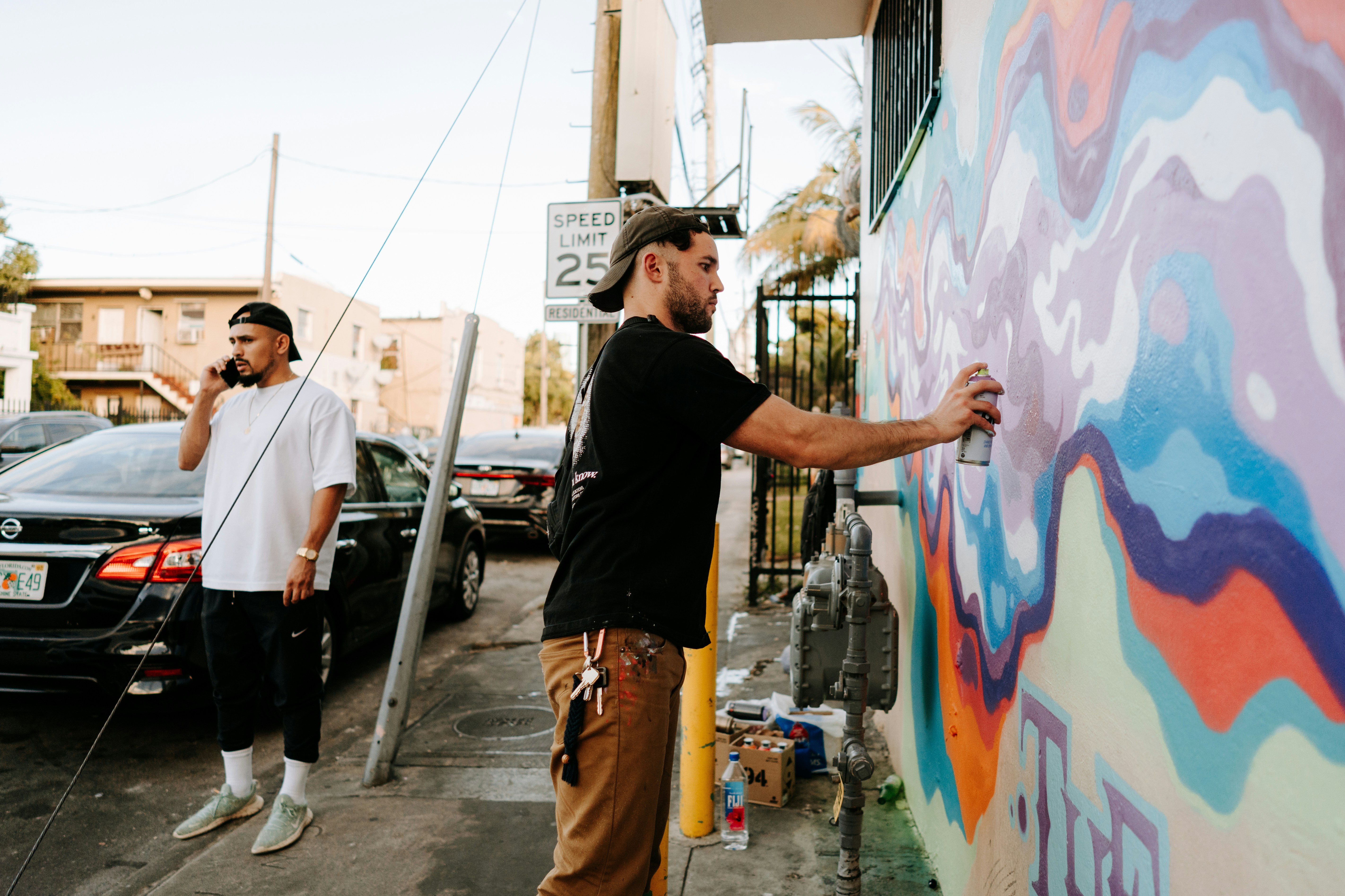 a couple of men standing next to a colorful wall