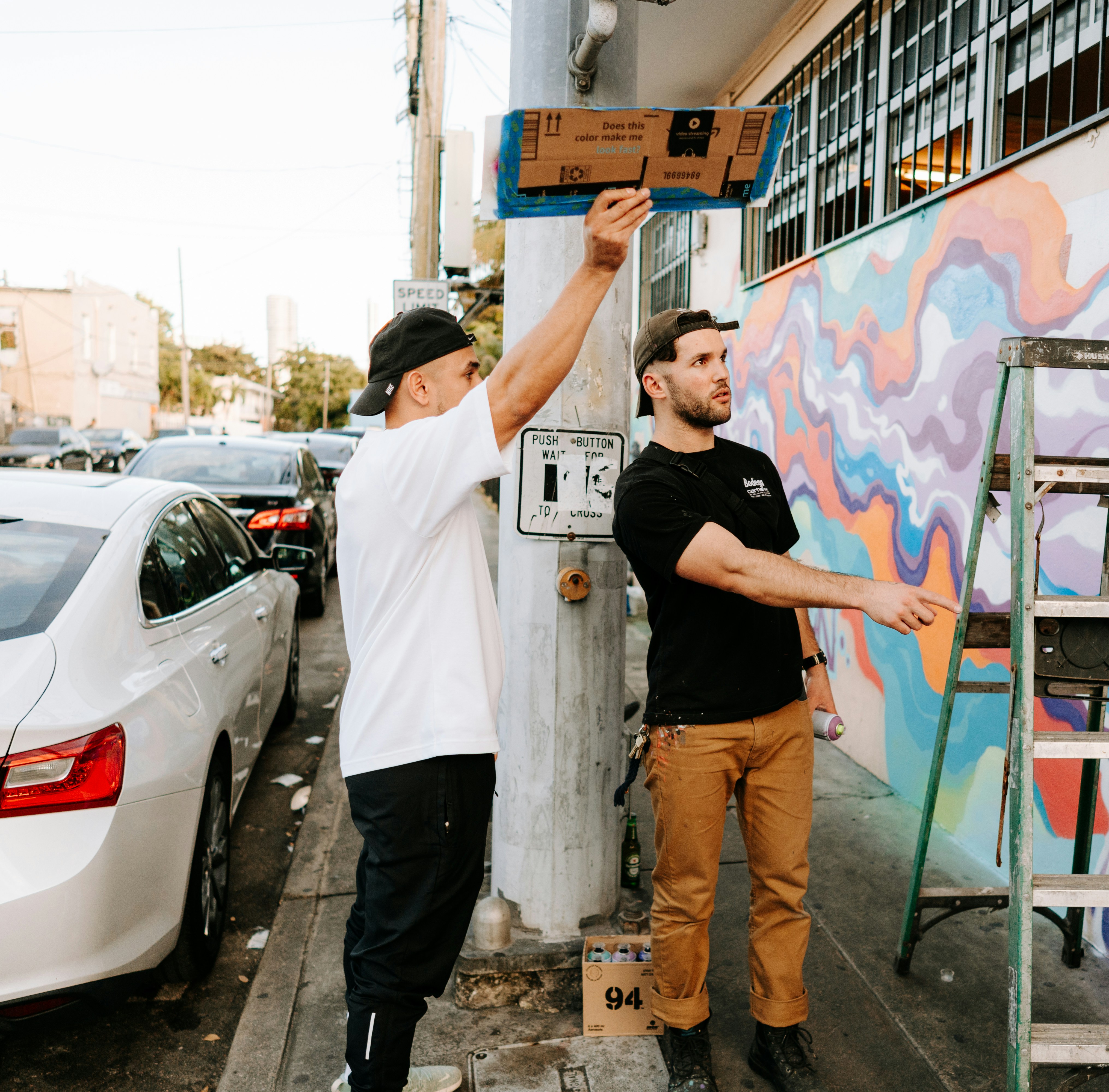 two men are painting a mural on the side of a building