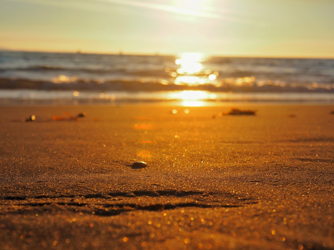 the sun is setting over the ocean on the beach,