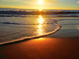 the sun is setting over the ocean on the beach